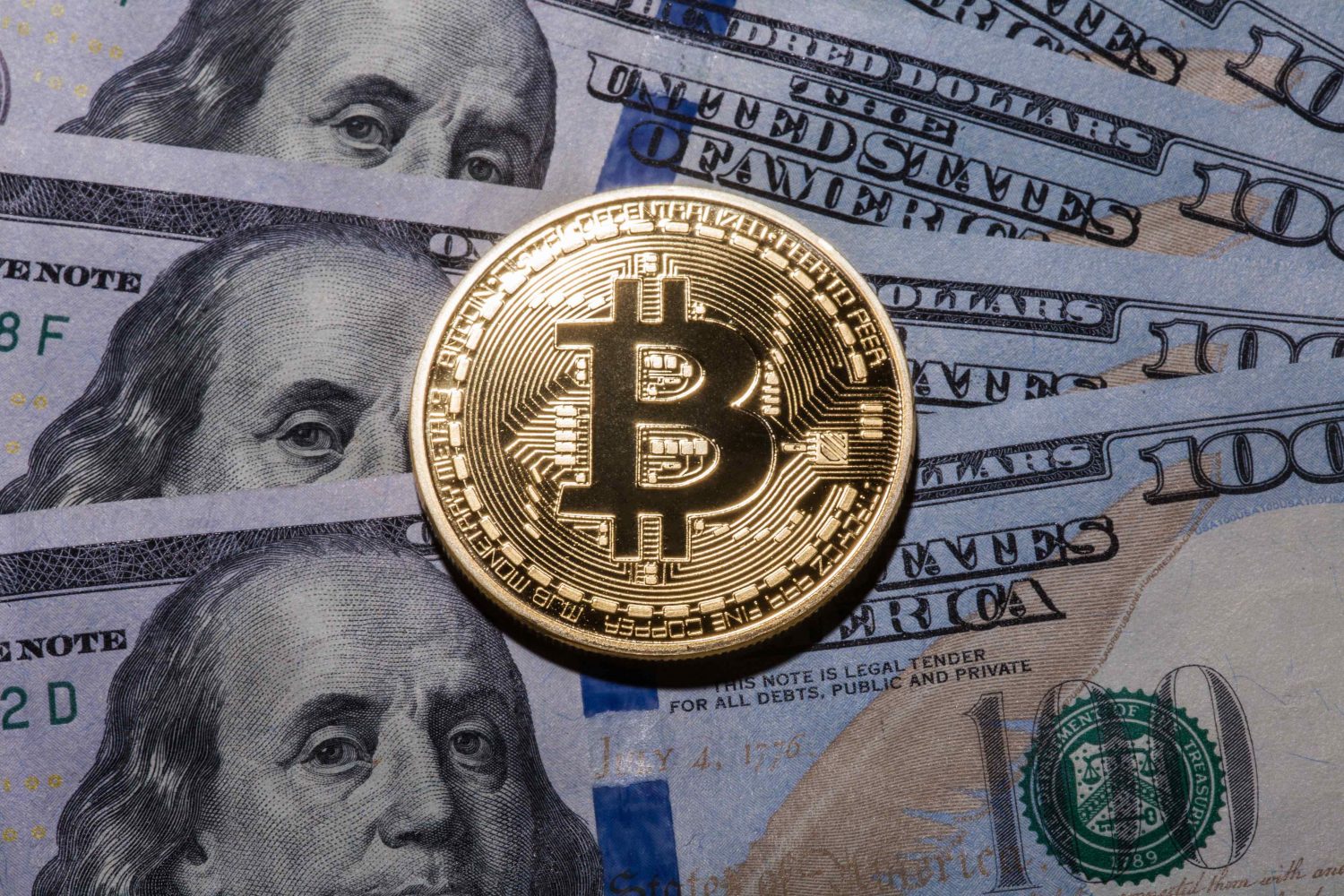 un bitcoin posé sur des billets de dollars